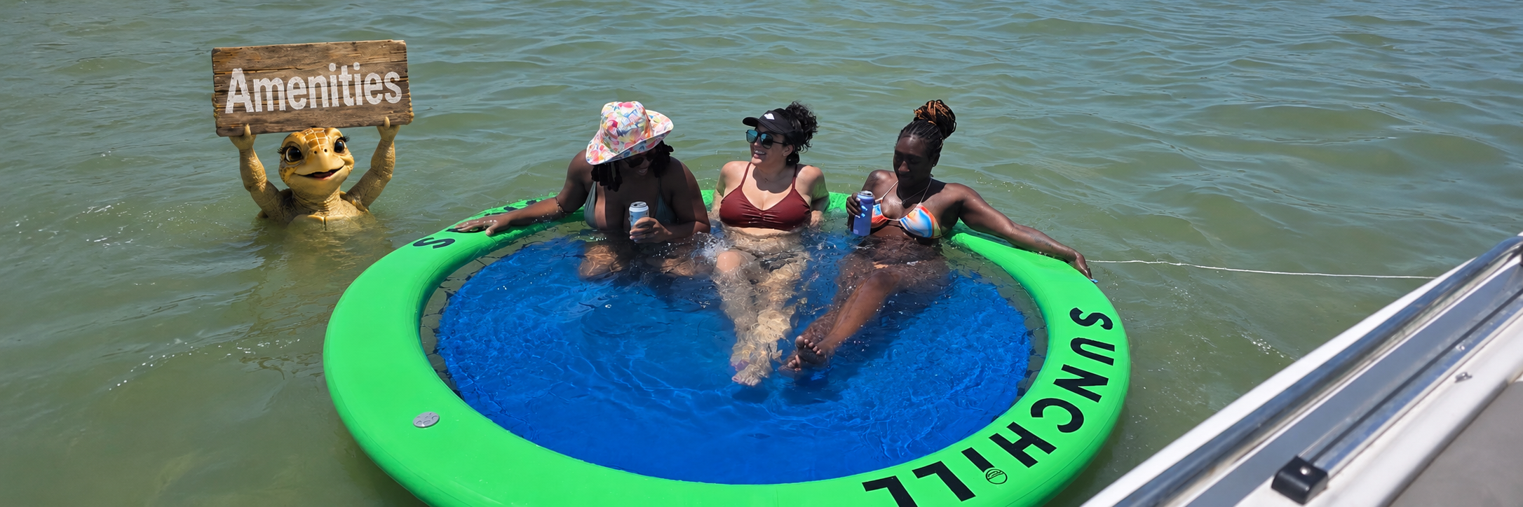 Tessa the sea turtle holding an Amenities sign beside guests relaxing on the Sunchill float