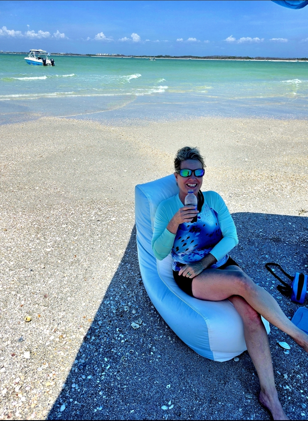 A guest sitting on the Sand Dollar Key sandbar in shallow clear water off Fort De Soto, Florida